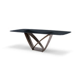 The Byron Dining Table featuring a sculptural brass metal base and smooth glass tabletop, styled in a contemporary dining room.